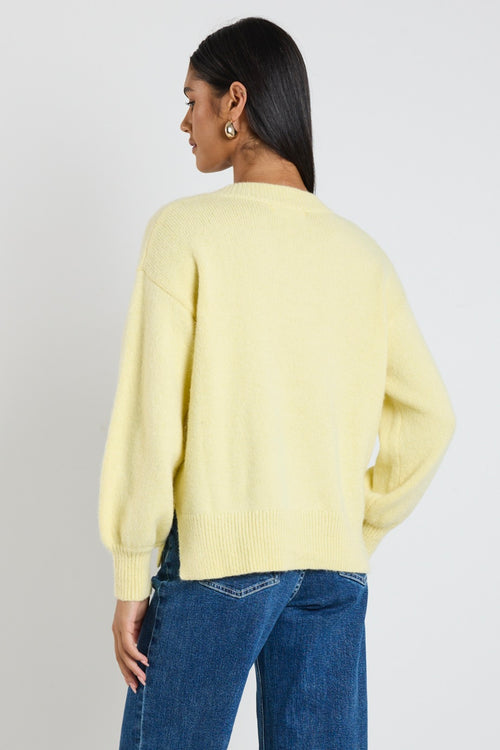 model wears a yellow knit jumper with blue jeans