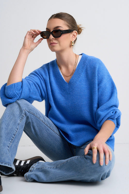 Model wears a blue jumper with jeans