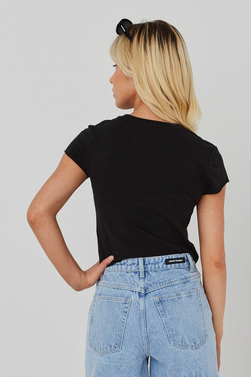 model wears black crop top and blue jeans