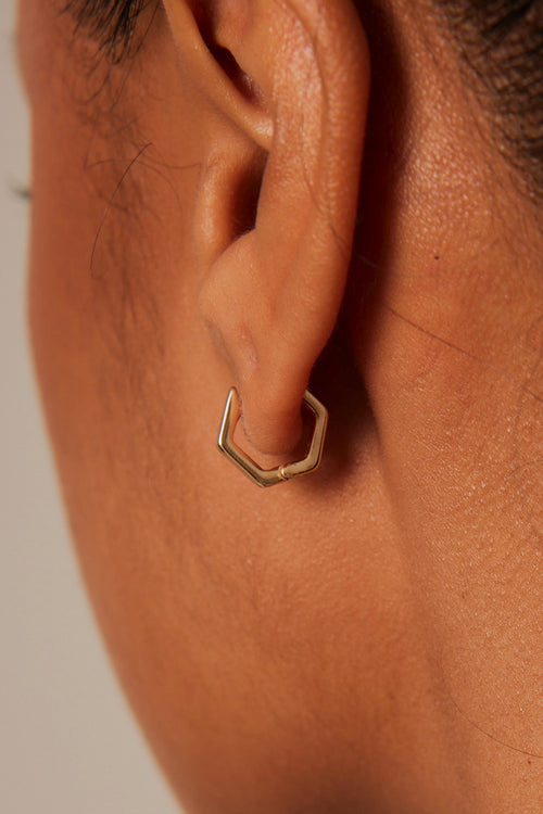 model in hexagonal gold earrings