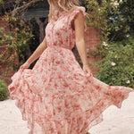 model wears a pink floral maxi dress with white sandals