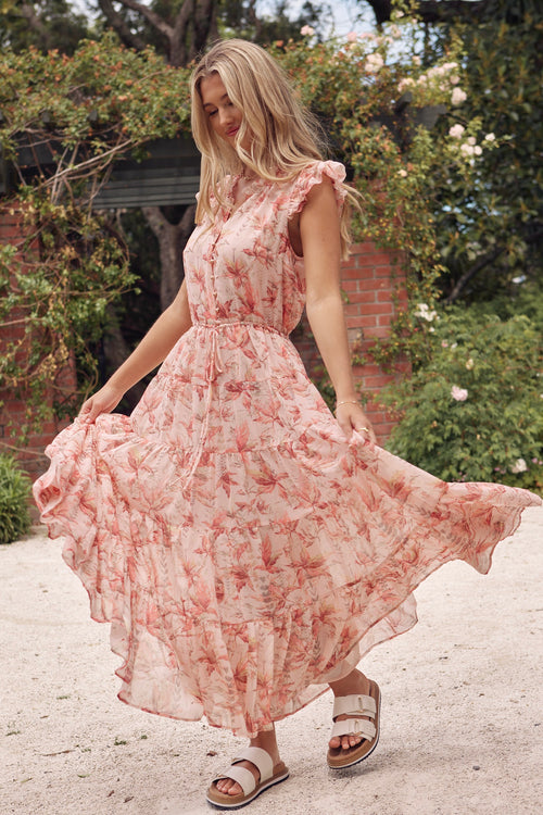 model wears a pink floral maxi dress with white sandals