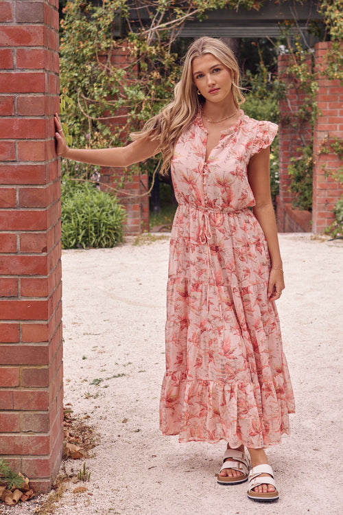 model wears a pink floral maxi dress with white sandals