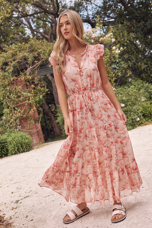 model wears a pink floral maxi dress with white sandals