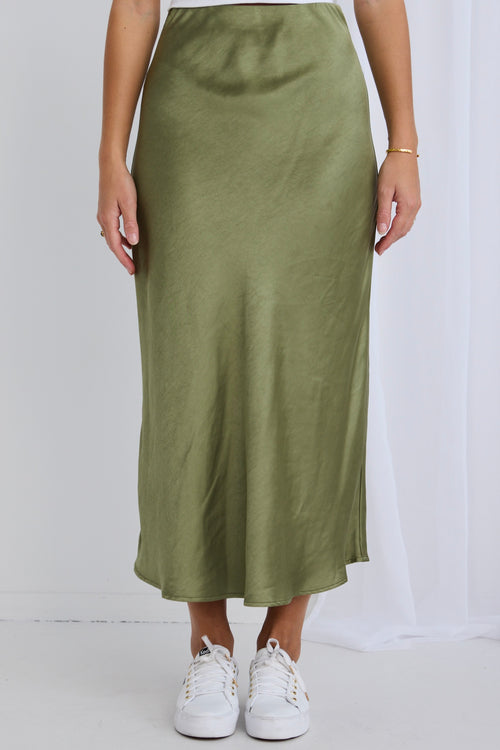 Model wears a green satin skirt with a white top and cardigan