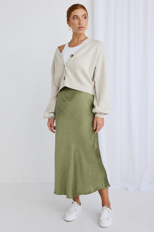 Model wears a green satin skirt with a white top and cardigan