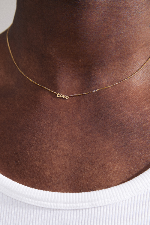 model wearing a gold chain adjustable necklace with a pendant reading 