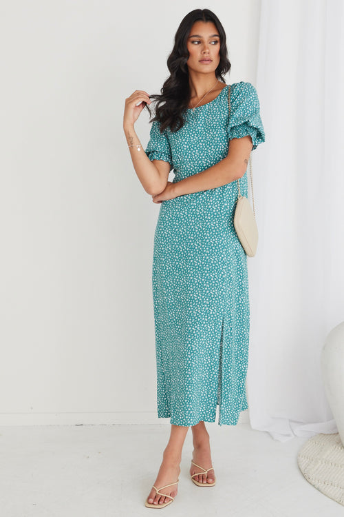 Model wearing long green spotty dress with heels and handbag