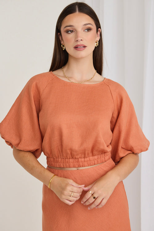 model wears an orange linen top