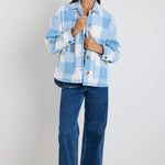 Model wears a blue check shacket with front pockets and a collar paired with blue jeans
