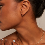 Model wears small diamante hoop earring with a gold chain necklace. 