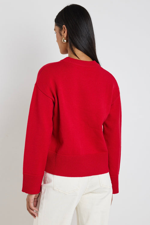 model wears a red knit jumper with white wide leg jeans