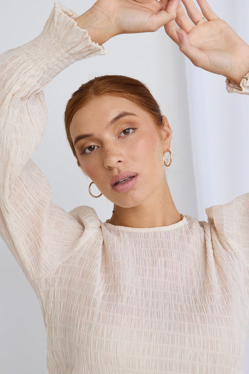 model wears a beige blouse