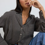 model wears a khaki stripe button up collared shirt with blue jeans