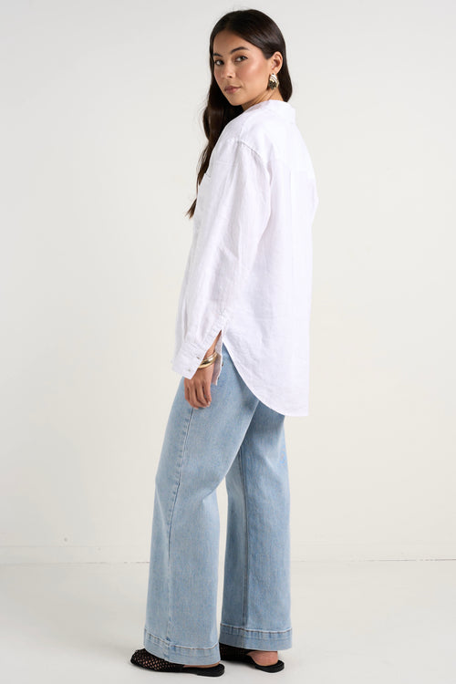 Model wears white linen shirt and light blue jeans