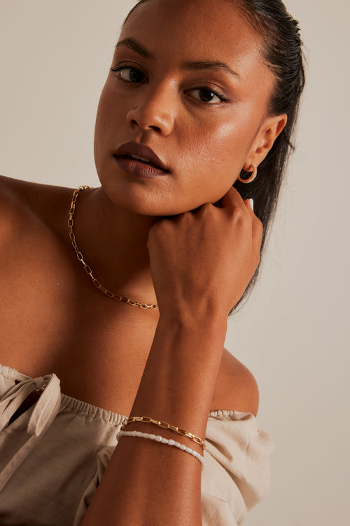 Model wears a gold chain bracelet 