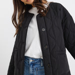model wears a black puffer jacket with blue jeans