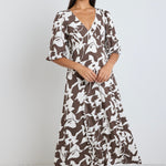 Model wears a brown pattern maxi dress with a v neckline. 