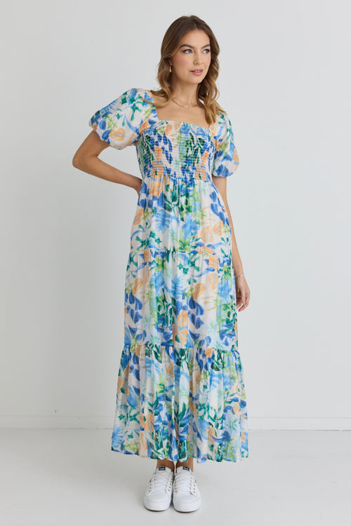 model is outside and wears and blue and orange floral maxi dress with sandals