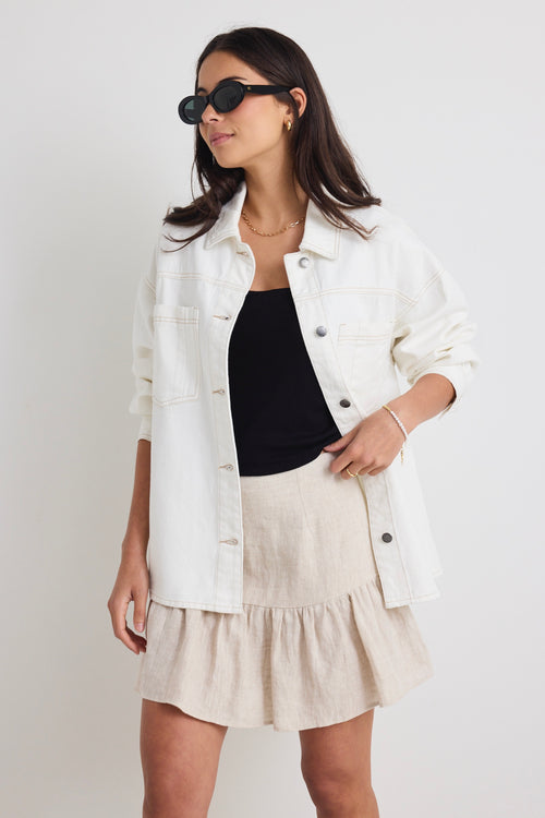 Model wears a ivory white denim jacket with front pockets and button up