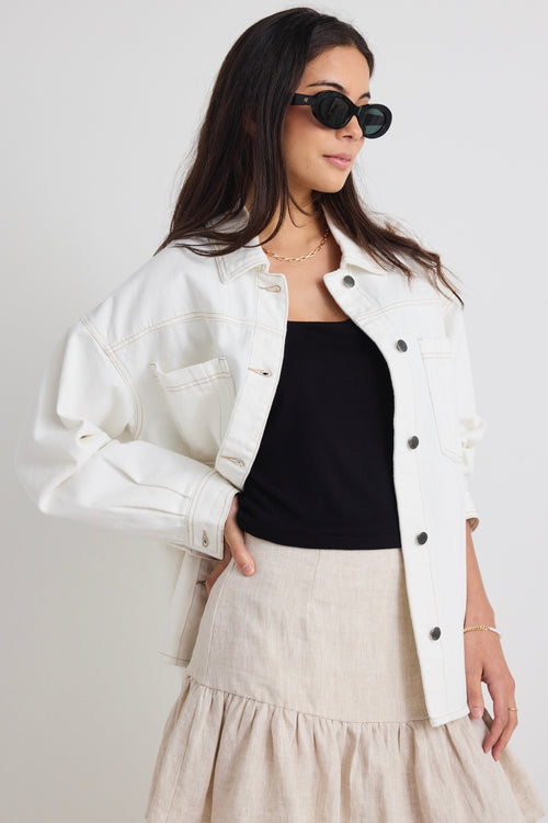 Model wears a ivory white denim jacket with front pockets and button up