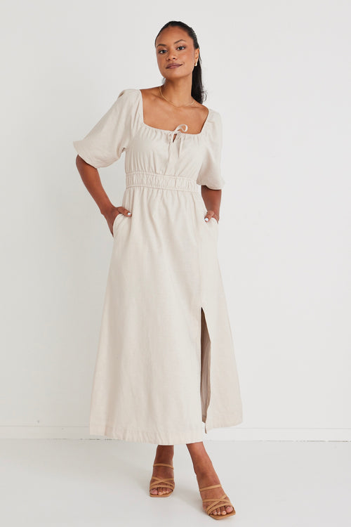 Model wears a linen  midi dress with a slit in the leg. 