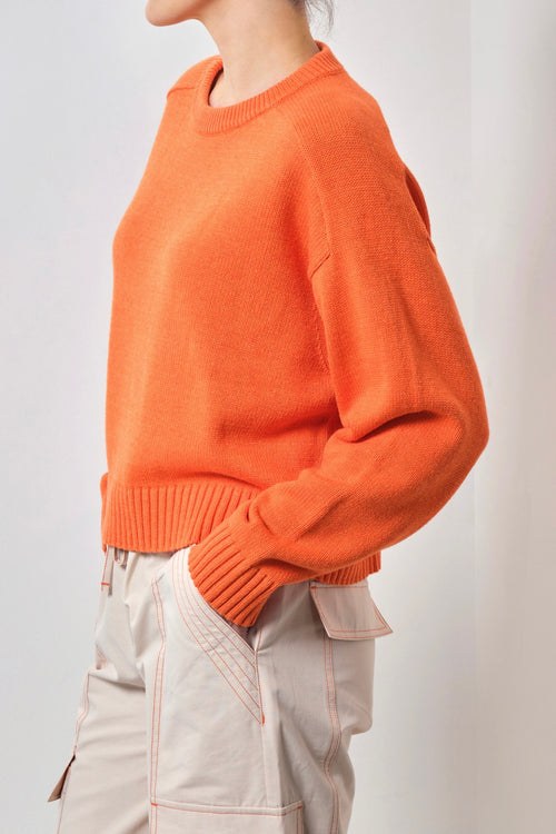 Model wears an orange knit 