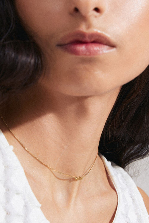 model wearing gold necklace with a pendant reading 