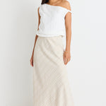 model wears white top and natural linen bias cut midi skirt