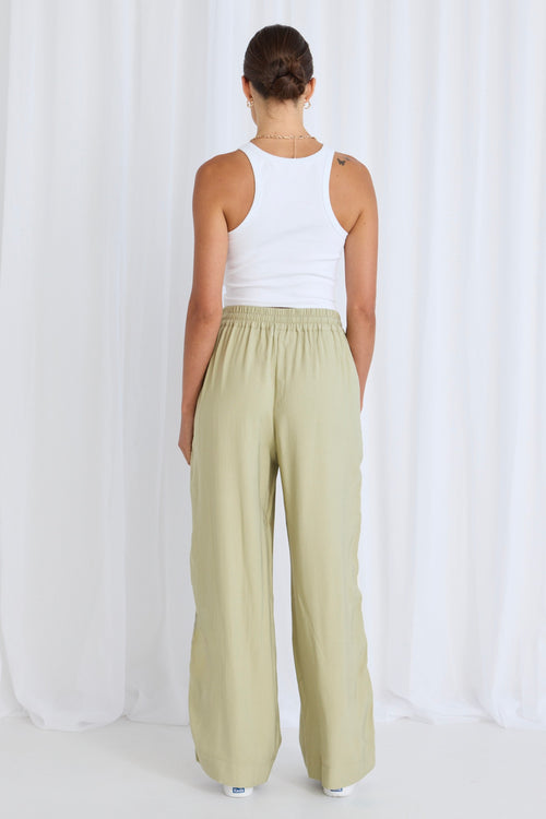 model wears green pants with a white tank