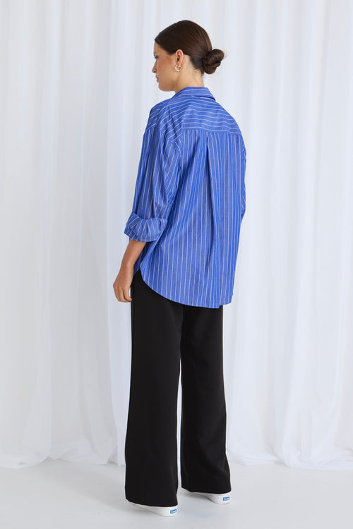 Model wears a blue stripe shirt with black pants