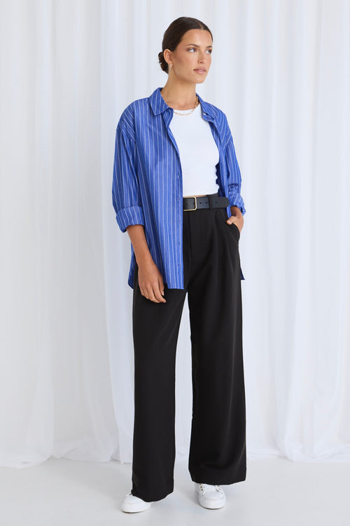 Model wears a blue stripe shirt with black pants