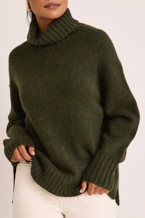 model wears a green turtle neck knit