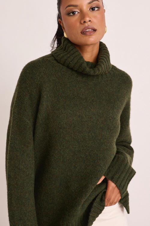 model wears a green turtle neck knit