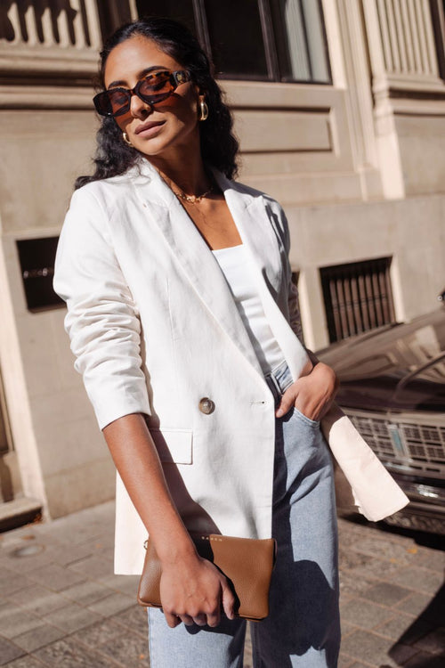 model wears beige linen blazer with blue jeans and a brown handbag