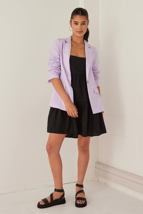 model wearing purple blazer over a black mini dress