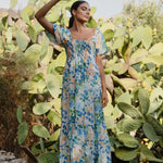 model is outside and wears and blue and orange floral maxi dress with sandals