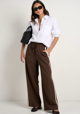 Model wears brown track pants