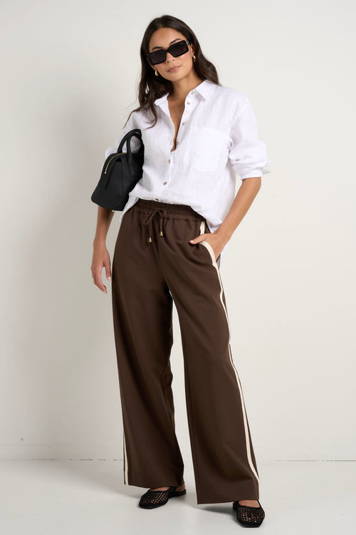 Model wears brown track pants