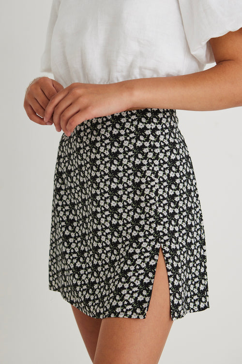 model wearing white top and black floral mini skirt