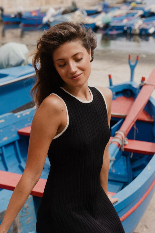 model wears black rib knit maxi dress outside by the water