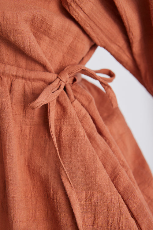 Model wears a terracotta top with a white denim skirt 