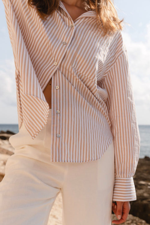 Model wears a stripe white and tan shirt 