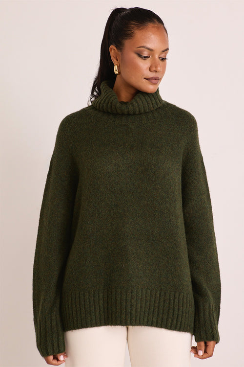 model wears a green turtle neck knit