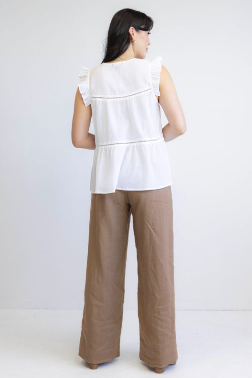 model wears white sleeveless top with brown pants